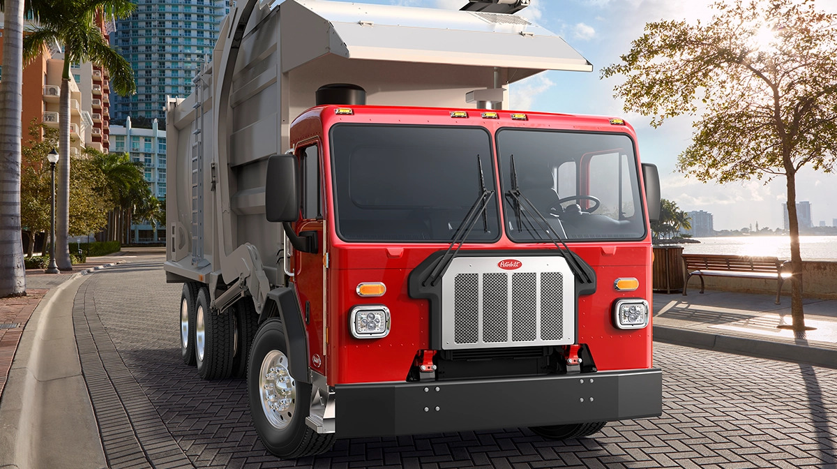 Red Peterbilt Model 520 refuse truck on a city street